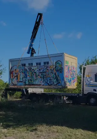 Ein Container hängt am Kranhaken und wird auf einen Lkw verladen